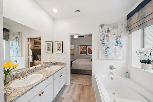 ensuite bathroom with ensuite bathroom, wood finished floors, visible vents, and a sink