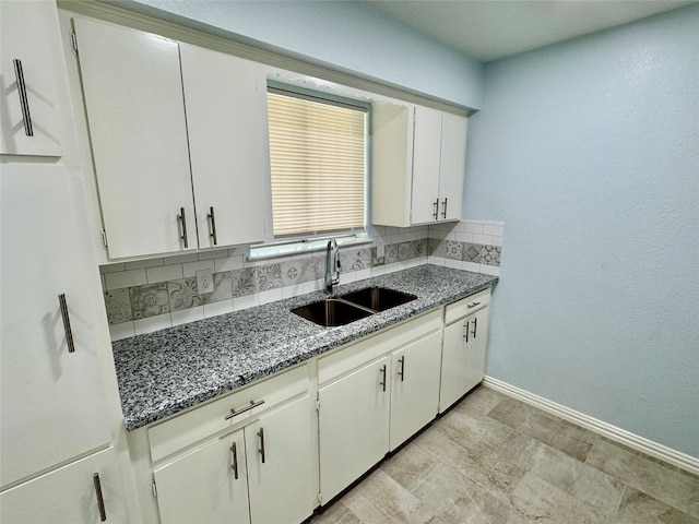 11615 Harrow St, Houston, TX 77093 - kitchen with a sink, dark stone countertops, white cabinetry, backsplash, and baseboards