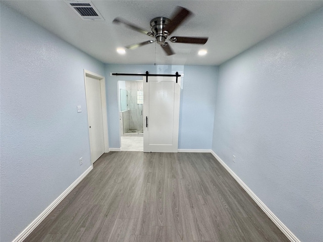 11615 Harrow St, Houston, TX 77093 - interior space featuring wood finished floors, a barn door, visible vents, a ceiling fan, and baseboards