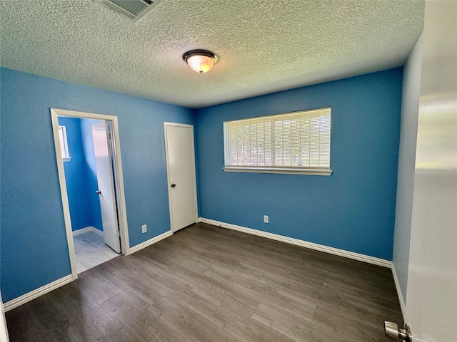 11615 Harrow St, Houston, TX 77093 - unfurnished bedroom featuring ensuite bathroom, wood finished floors, a textured ceiling, visible vents, and baseboards