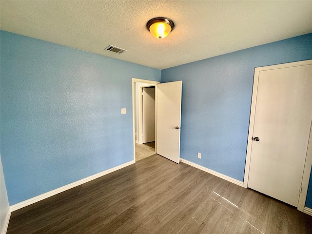 11615 Harrow St, Houston, TX 77093 - unfurnished bedroom featuring wood finished floors, a textured ceiling, visible vents, baseboards, and a textured wall