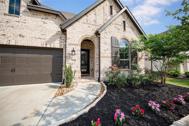 french country style house featuring an attached garage, brick siding, and driveway