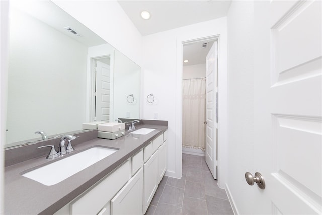 bathroom with a sink, double vanity, visible vents, and tile patterned floors