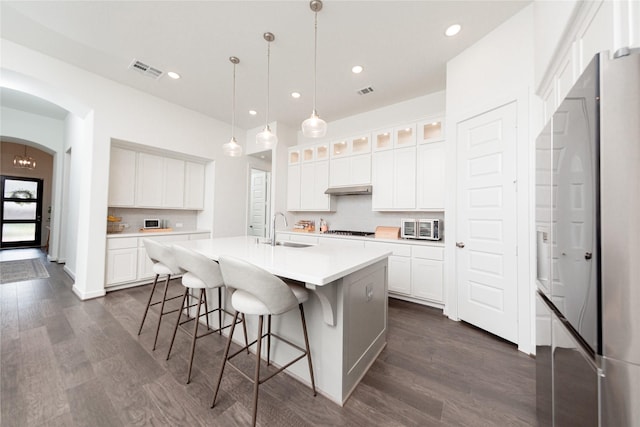 kitchen with a sink, a breakfast bar, visible vents, gas cooktop, and stainless steel fridge
