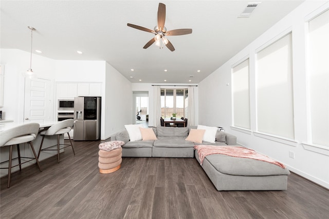 living area with baseboards, dark wood-style floors, a ceiling fan, and visible vents