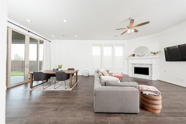 living room featuring a premium fireplace, a ceiling fan, dark wood-type flooring, and recessed lighting