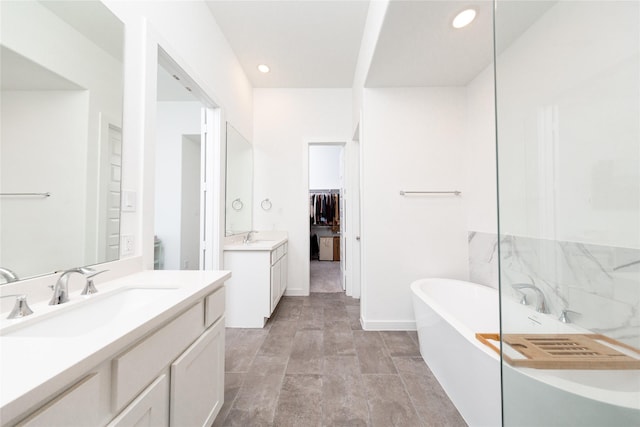full bathroom featuring a sink, recessed lighting, two vanities, and a freestanding tub