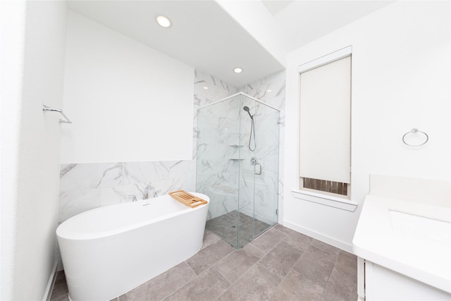 full bathroom featuring tile walls, recessed lighting, vanity, a freestanding tub, and a marble finish shower