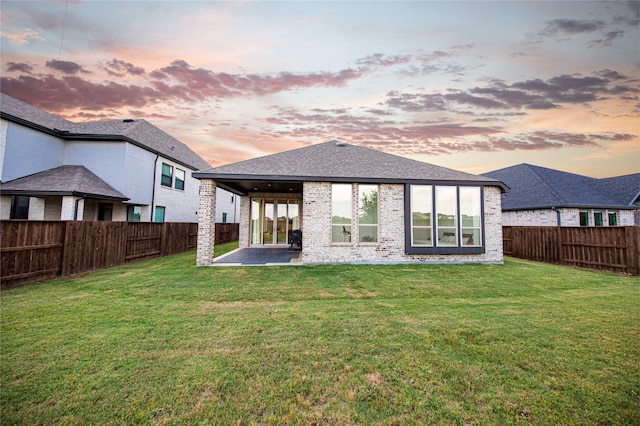rear view of property featuring a patio, a lawn, and a fenced backyard