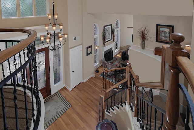 foyer featuring baseboards, visible vents, a fireplace, light wood finished floors, and a notable chandelier