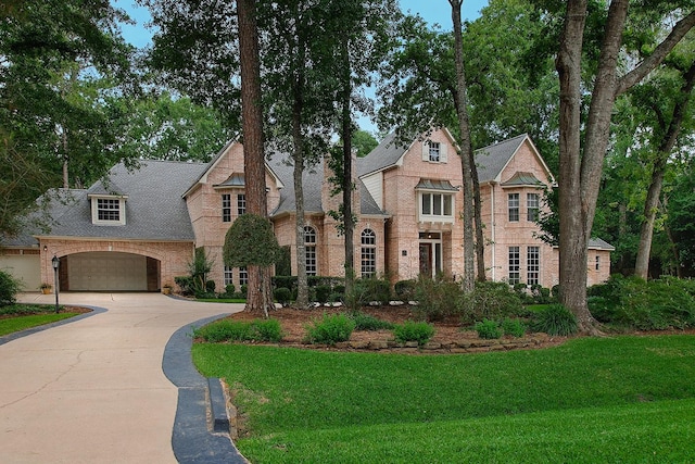 view of front facade featuring an attached garage, a front yard, brick siding, and driveway