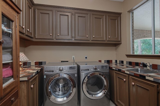 laundry area featuring a sink, washer and clothes dryer, and cabinet space