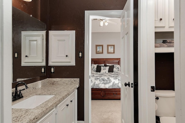 ensuite bathroom with vanity, ensuite bathroom, toilet, and a ceiling fan