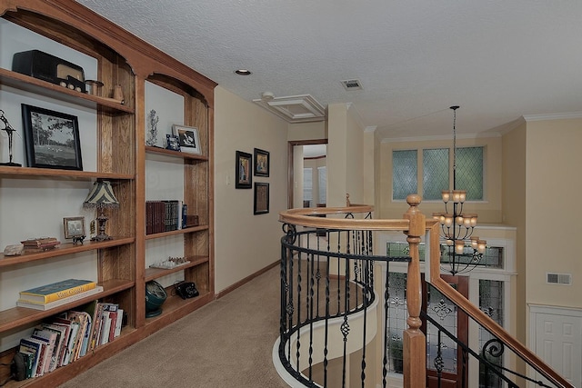 hall featuring carpet, baseboards, an upstairs landing, visible vents, and a notable chandelier