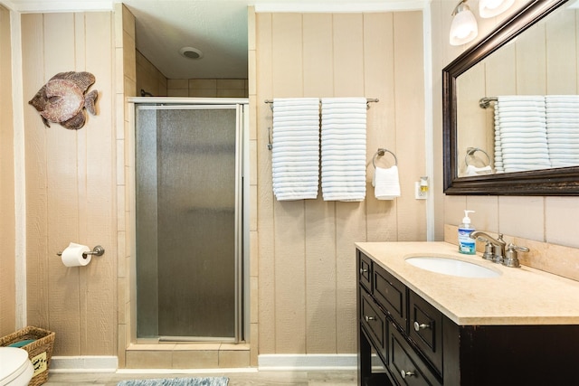 13022 Coronado Dr, Freeport, TX 77541 - bathroom with toilet, wood finished floors, baseboards, a shower stall, and vanity