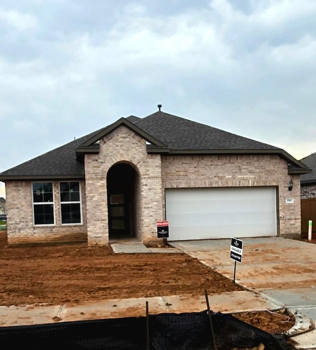 view of front of house featuring a shingled roof, concrete driveway, brick siding, and a garage