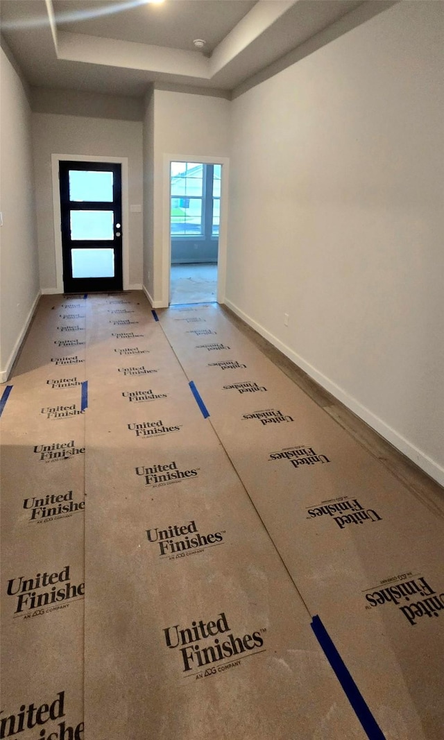 interior space with a tray ceiling and baseboards