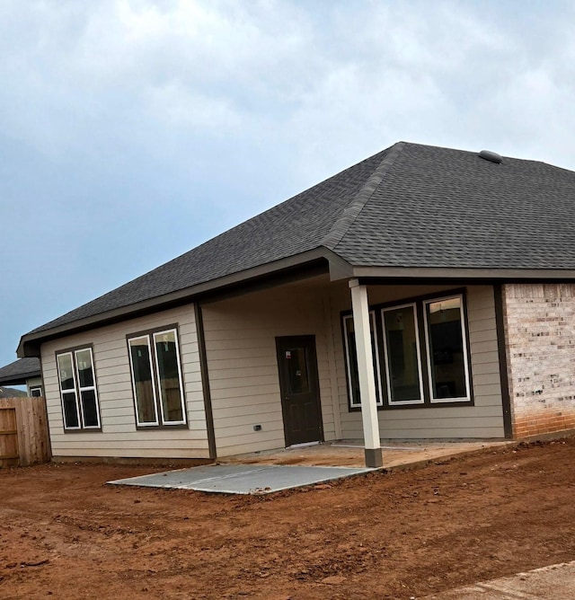 back of house featuring a shingled roof, a patio area, and fence