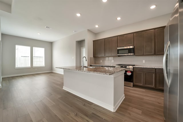 2563 Newport Breeze Dr, Katy, TX 77493 - kitchen featuring stainless steel appliances, a kitchen island with sink, light stone countertops, dark wood-style floors, and recessed lighting
