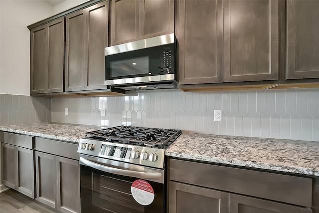 2563 Newport Breeze Dr, Katy, TX 77493 - kitchen with stainless steel appliances, backsplash, light stone countertops, and dark brown cabinets