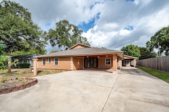 ranch-style house featuring stucco siding, concrete driveway, a carport, and fence