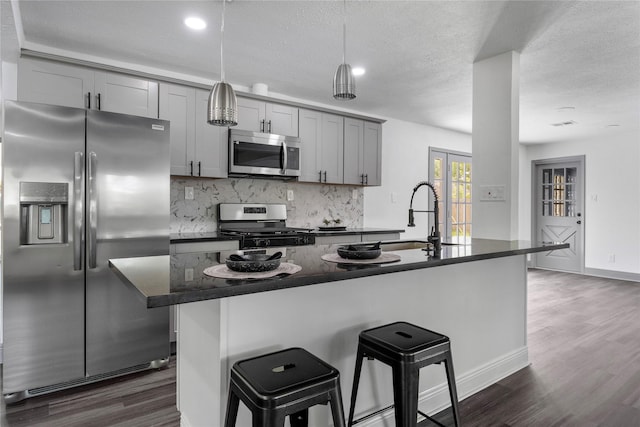702 Pennington St, Houston, TX 77022 - kitchen featuring a sink, stainless steel appliances, gray cabinets, backsplash, and dark countertops