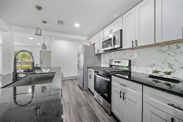702 Pennington St, Houston, TX 77022 - kitchen with decorative light fixtures, a sink, wood finished floors, stainless steel appliances, and tasteful backsplash