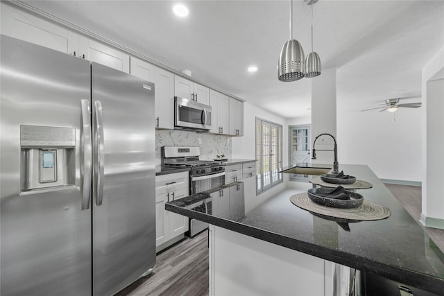 702 Pennington St, Houston, TX 77022 - kitchen with a sink, dark stone countertops, wood finished floors, tasteful backsplash, and appliances with stainless steel finishes