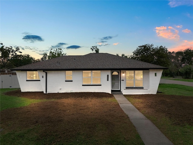 702 Pennington St, Houston, TX 77022 - view of front of home with a yard, a shingled roof, brick siding, and fence