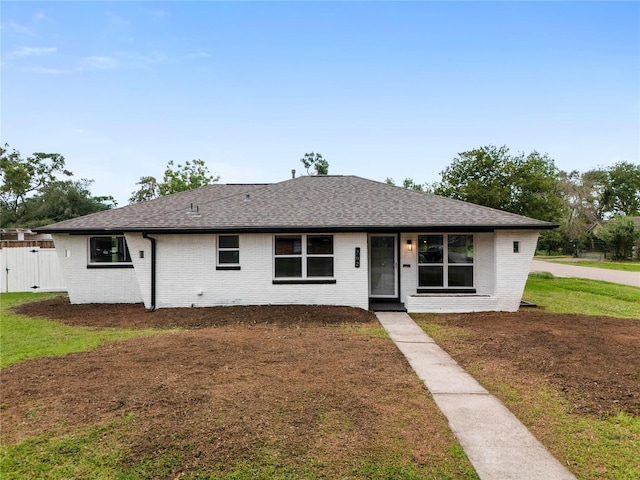 702 Pennington St, Houston, TX 77022 - view of front of house featuring roof with shingles, fence, brick siding, and a front yard