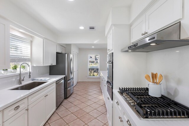 kitchen with a sink, stainless steel appliances, white cabinets, visible vents, and under cabinet range hood