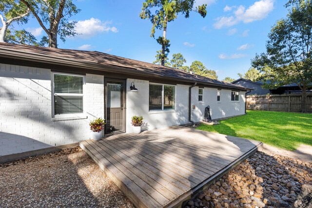 rear view of house with a yard, fence, and a wooden deck
