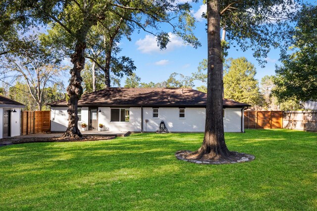 rear view of house with fence and a lawn