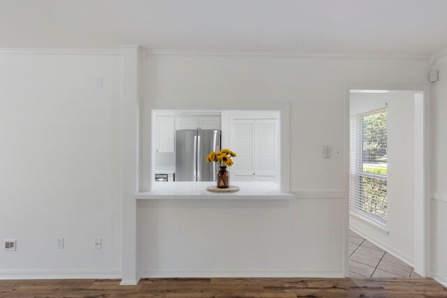 interior space with freestanding refrigerator, white cabinetry, crown molding, wood finished floors, and light countertops