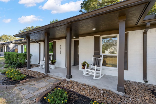 view of exterior entry with covered porch and brick siding