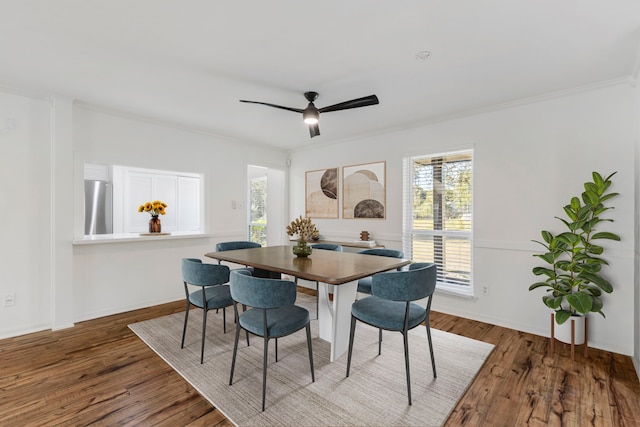 dining room with wood finished floors, crown molding, ceiling fan, and baseboards