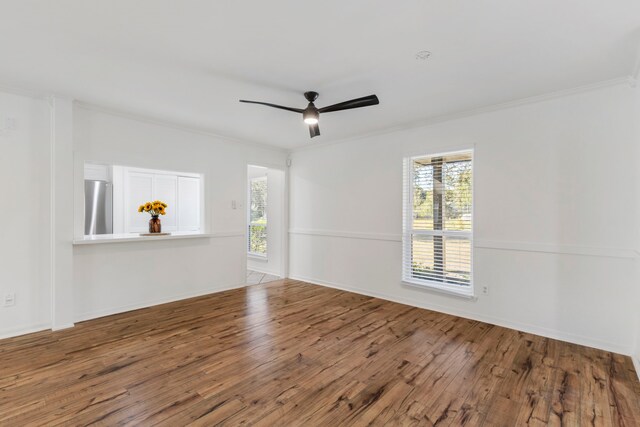 spare room with a ceiling fan, a healthy amount of sunlight, crown molding, and wood finished floors