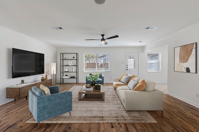 living area with a ceiling fan, wood finished floors, baseboards, and crown molding