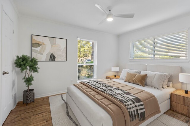 bedroom featuring wood finished floors, crown molding, multiple windows, baseboards, and a ceiling fan