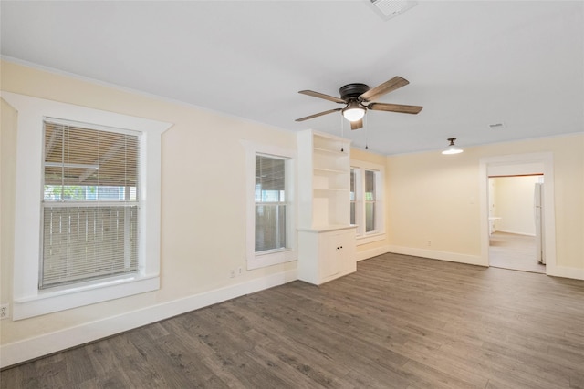 unfurnished room with dark wood-style flooring, plenty of natural light, baseboards, and visible vents