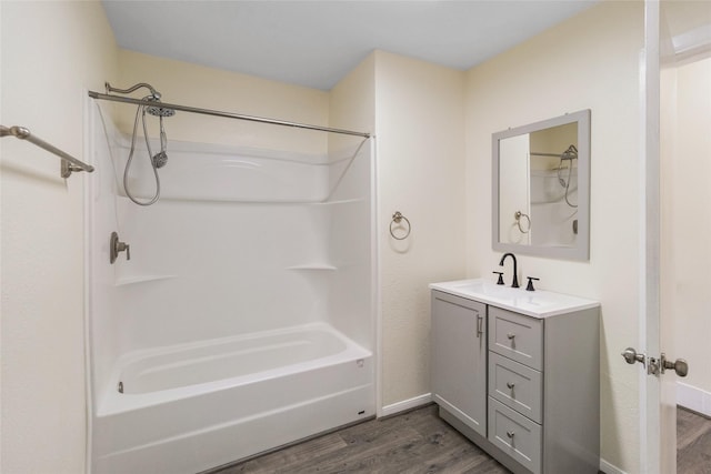 full bathroom with baseboards, wood finished floors, vanity, and washtub / shower combination