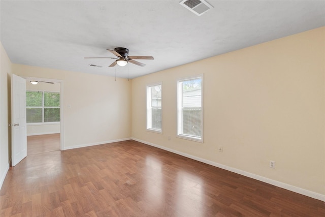 empty room with ceiling fan, baseboards, visible vents, and wood finished floors