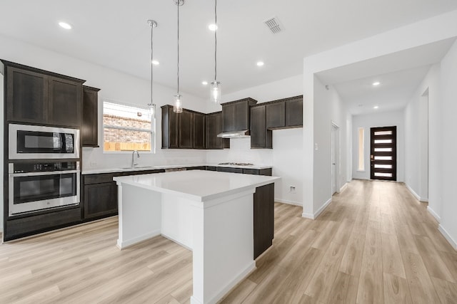 kitchen with a sink, stainless steel appliances, visible vents, a kitchen island, and dark brown cabinets