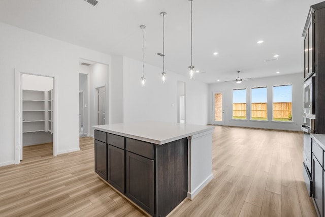 21818 Wycombe Terrace Way, Cypress, TX 77433 - kitchen featuring a ceiling fan, light wood-style flooring, light countertops, dark brown cabinets, and hanging light fixtures