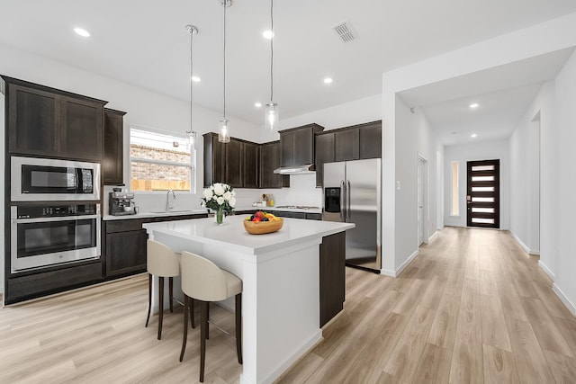 21818 Wycombe Terrace Way, Cypress, TX 77433 - kitchen featuring appliances with stainless steel finishes, a sink, a center island, light countertops, and dark brown cabinetry