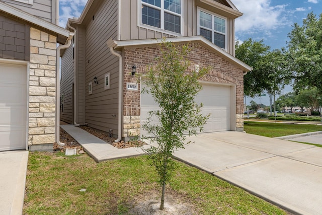 15010 Eagle Feather Ct, Houston, TX 77090 - view of side of home with an attached garage, stone siding, brick siding, concrete driveway, and board and batten siding