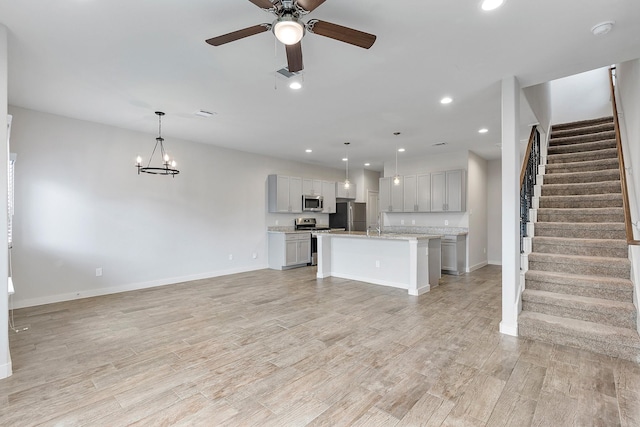 15010 Eagle Feather Ct, Houston, TX 77090 - unfurnished living room with light wood-style flooring, recessed lighting, baseboards, ceiling fan with notable chandelier, and stairs