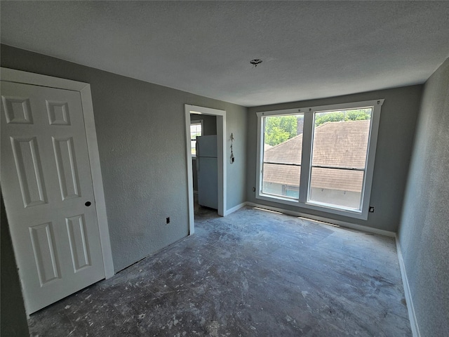 3229 Holman St Unit 4, Houston, TX 77004 - unfurnished bedroom with a textured wall, concrete floors, a textured ceiling, and freestanding refrigerator