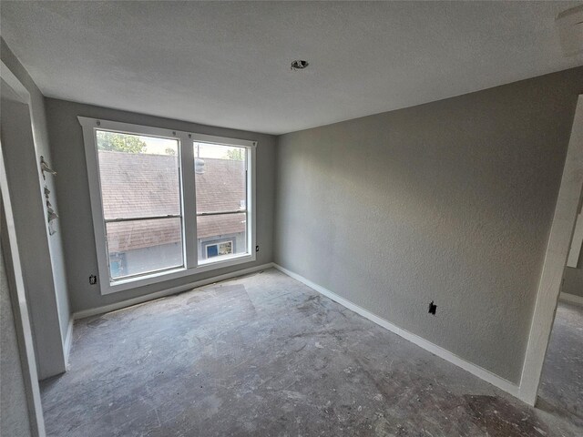3229 Holman St Unit 4, Houston, TX 77004 - spare room with a textured wall, baseboards, unfinished concrete floors, and a textured ceiling