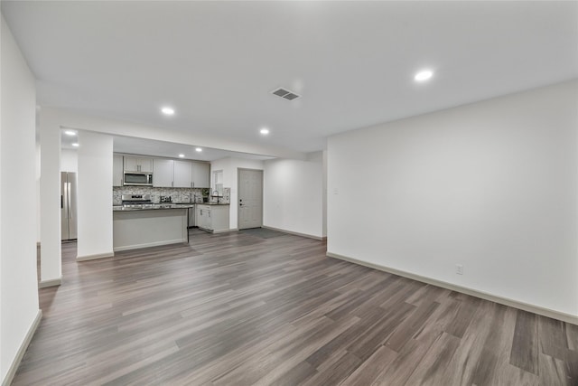 9211 Helmers St, Houston, TX 77022 - unfurnished living room featuring recessed lighting, baseboards, visible vents, a sink, and wood finished floors